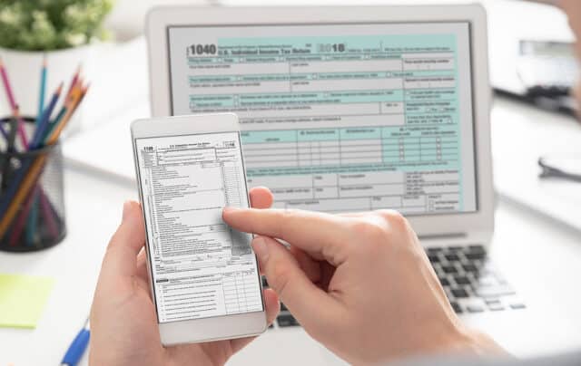 man checking his tax forms on his smartphone and computer