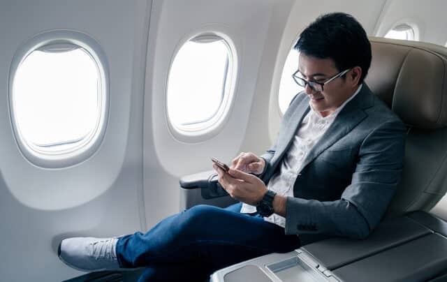 Man travelling on a plane checking his phone
