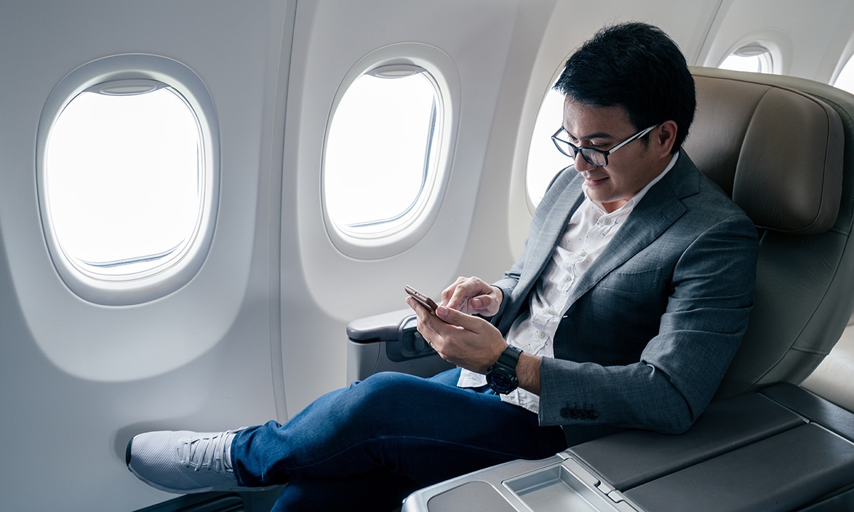 Man travelling on a plane checking his phone
